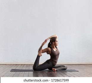 Young And Fit Woman Practicing Yoga Indoor In The Class. Stretching Exercise In The Day Light. Sport, Fitness, Health Care And Lifestyle.