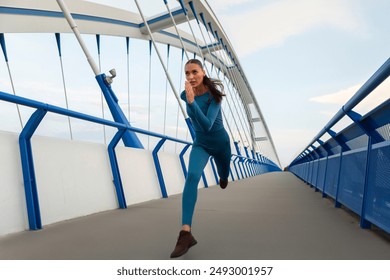 Young fit woman running in spacious pedestrian bridge, preparing for marathon, lady having evening workout outdoors - Powered by Shutterstock