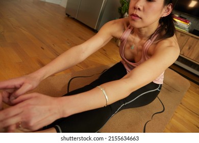 Young Fit Woman Sitting On Exercise Mat Touching Feet