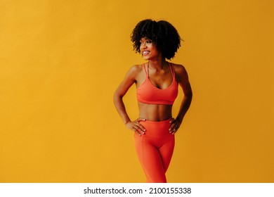 young fit woman in sportswear posing isolated on yellow background