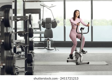Young fit woman in sportswear riding a stationary bike at a gym
