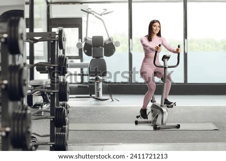 Young fit woman in sportswear riding a stationary bike at a gym