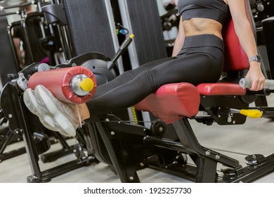 Young fit woman trains quadriceps, leg muscles in exercise machine. Attractive girl working out in the gym
