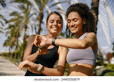 Young fit women looking at smartwatch and counting calories burned. Healthy life concept 