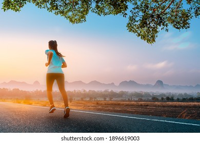 Young fitness Asian woman is running and jogging an outdoor workout on the road in the morning for lifestyle health.