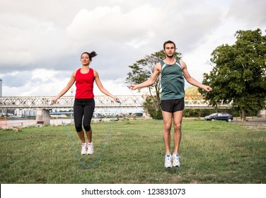 Young fitness couple exercising outdoor - jumping with skipping rope