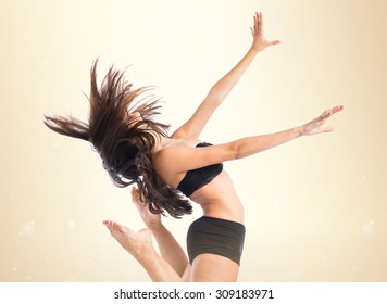 Young fitness female jumping over ocher background