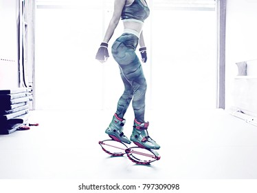 young fitness girl posing on kangoo training boot