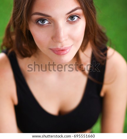 Young fitness girl sitting on green grass
