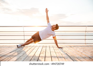 Young fitness man doing yoga exercise outdoors at the beach pier - Powered by Shutterstock