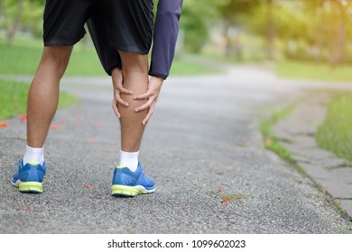 Young fitness man holding his sports leg injury, muscle painful during training. Asian runner having calf ache and problem after running and exercise outside in summer - Shutterstock ID 1099602023