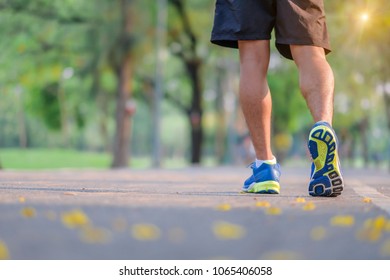 Young Fitness Man Legs Walking In The Park Outdoor, Male Runner Running On The Road Outside, Asian Athlete Jogging And Exercise On Footpath In Sunlight Morning. Sport,healthy And Wellness Concepts