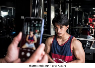 A young fitness model flexes his arms and has his picture taken to monitor his progress at the gym. Documenting physical development and muscle gains.