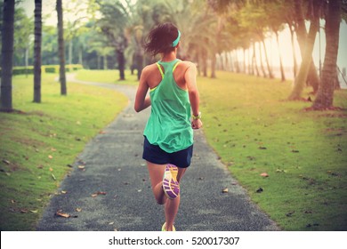 Young fitness sportswoman runner running on tropical park trail - Powered by Shutterstock