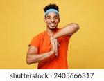 Young fitness trainer instructor sporty man sportsman wear orange t-shirt do exercise for palm hold move hands spend time in home gym isolated on plain yellow background. Workout sport fit abs concept