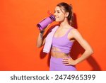 Young fitness trainer instructor sporty woman sportsman wear purple top clothes spend time in home gym hold bottle drink water towel isolated on plain orange background. Workout sport fit abs concept