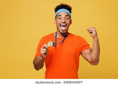 Young fitness trainer instructor sporty man sportsman wear orange t-shirt show golden medal award do winner gesture spend time in gym isolated on plain yellow background. Workout sport fit abs concept - Powered by Shutterstock