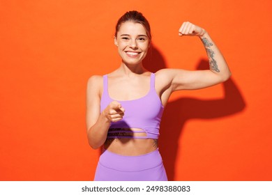 Young fitness trainer sporty woman sportsman wear purple top clothes spend time in home gym show muscles point finger camera on you isolated on plain orange background. Workout sport fit abs concept - Powered by Shutterstock