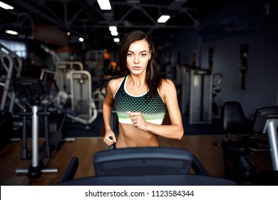 Young Fitness Woman Doing Cardio Exercises At The Gym Running On A Treadmill. Female Runner Training At The Health Club.