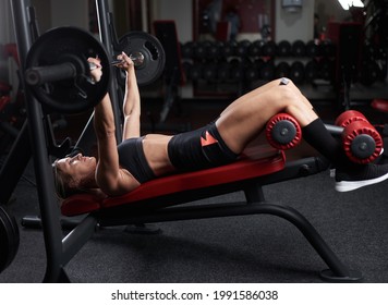 Young fitness woman doing incline bench press with barbell for chest workout - Shutterstock ID 1991586038