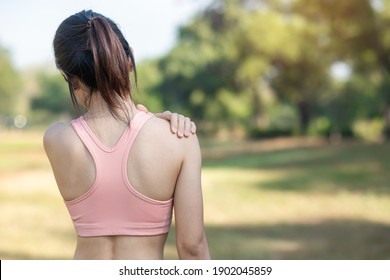 Young Fitness Woman Holding Her Sports Injury Shoulder, Muscle Painful During Training. Asian Runner Female Having Body Problem After Exercise Outside In Summer