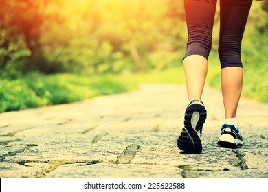 young fitness woman legs walking at forest trail 