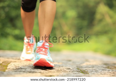 young fitness woman legs walking on forest trail 
