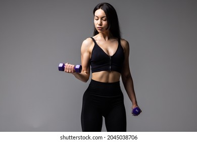 Young Fitness Woman Lifting Dumbell On Gray Background