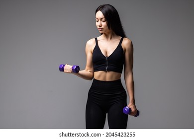 Young Fitness Woman Lifting Dumbell On Gray Background