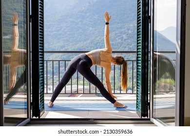 Young fitness woman practicing yoga poses at the baclcony in the morning. Slim girl doing morning yoga routine - Powered by Shutterstock