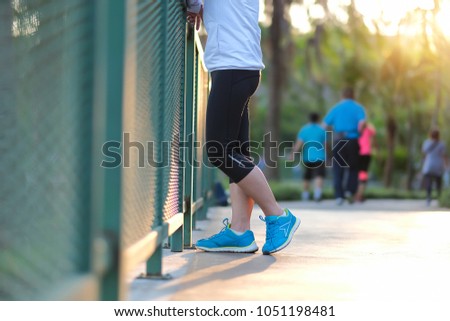 young fitness woman relaxing after walking in the park outdoor, female runner running on the road outside, asian athlete jogging and exercise on footpath in sunlight morning.Sport and wellness concept