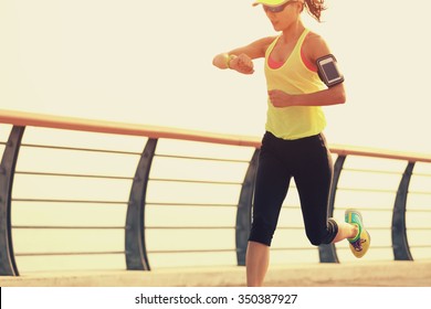 Young Fitness Woman Runner Checking Her Running Time From Smart Watch At Seaside