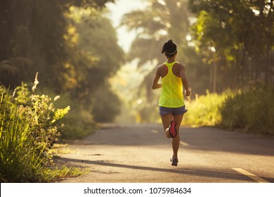 Young fitness woman runner running on the forest trail