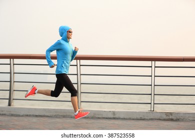 young fitness woman runner running at seaside