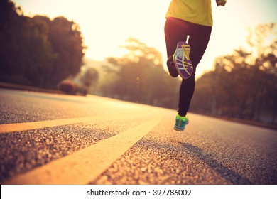 young fitness woman runner running on sunrise road - Shutterstock ID 397786009