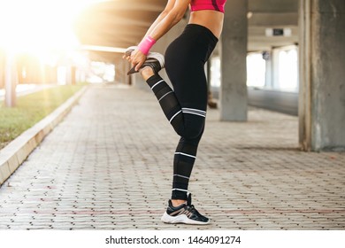 Young fitness woman runner stretching legs before run. Fit woman exercising outdoors. Healthy young female athlete doing fitness workout. - Shutterstock ID 1464091274