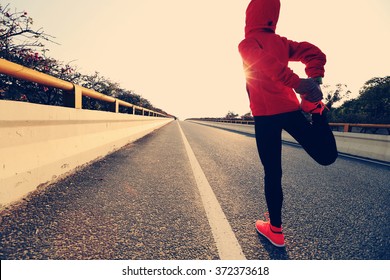 young fitness woman runner stretching legs before run
