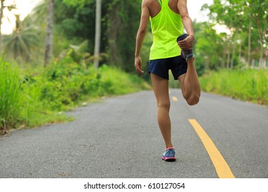 Young Fitness Woman Runner Stretching Legs Before Running At Morning Tropical Forest Trail 