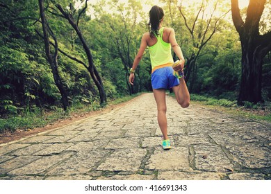 Young Fitness Woman Runner Warming Up In Forest