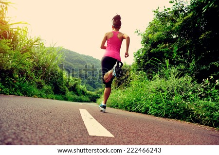 young fitness woman running at forest trail 