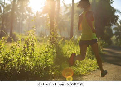 Young fitness woman running at morning tropical forest trail  - Shutterstock ID 609287498