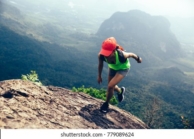 Young fitness woman running up to the mountain top
