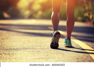 Young fitness woman running on morning tropical forest trail 