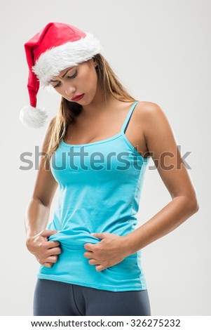 Young fitness woman showing her belly fat after Christmas.