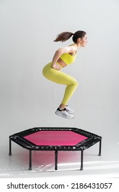 young fitness woman In sportswear jumping on sport trampoline White background - Shutterstock ID 2186431057