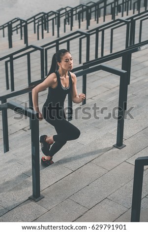 Young fitness woman in sportswear running up on stadium stairs
