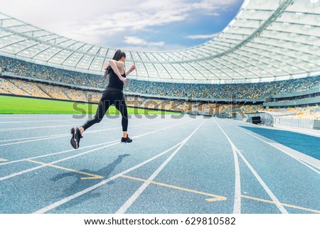 Young fitness woman in sportswear running on running track stadium