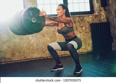 Young Fitness Woman Standing With Heavy Weight Barrel. Soft Warm Sunlight Light.