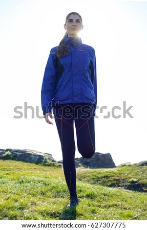 Young Fitness Woman Stretching her Legs in the Mountains in Sun Rays. Female Runner Doing Stretches Outdoor. Healthy Lifestyle Concept.