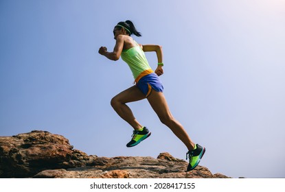 Young Fitness Woman Trail Runner Running To Rocky Mountain Top On Seaside